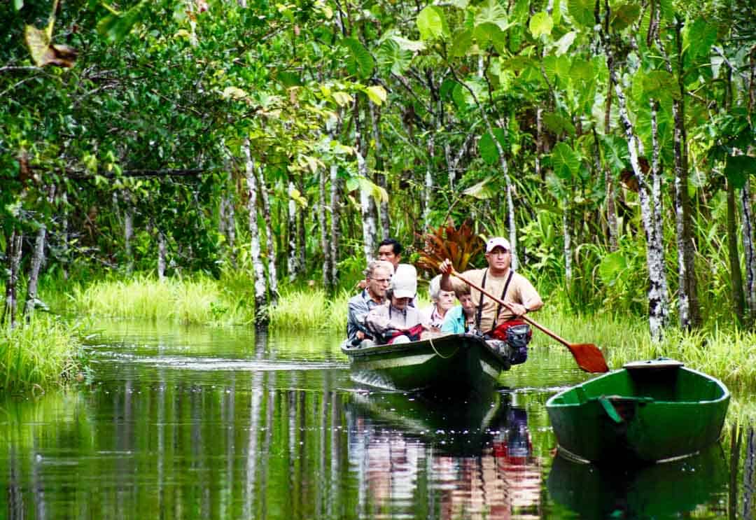 A small boat paddles guests through a winding canal to the Pilchicocha Lagoon and Sacha Lodge.