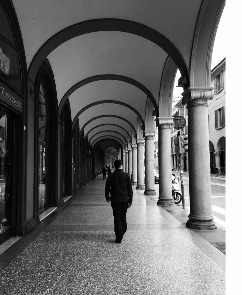 Walking through one of one of the stately colonnaded arcades of Bologna, Italy.