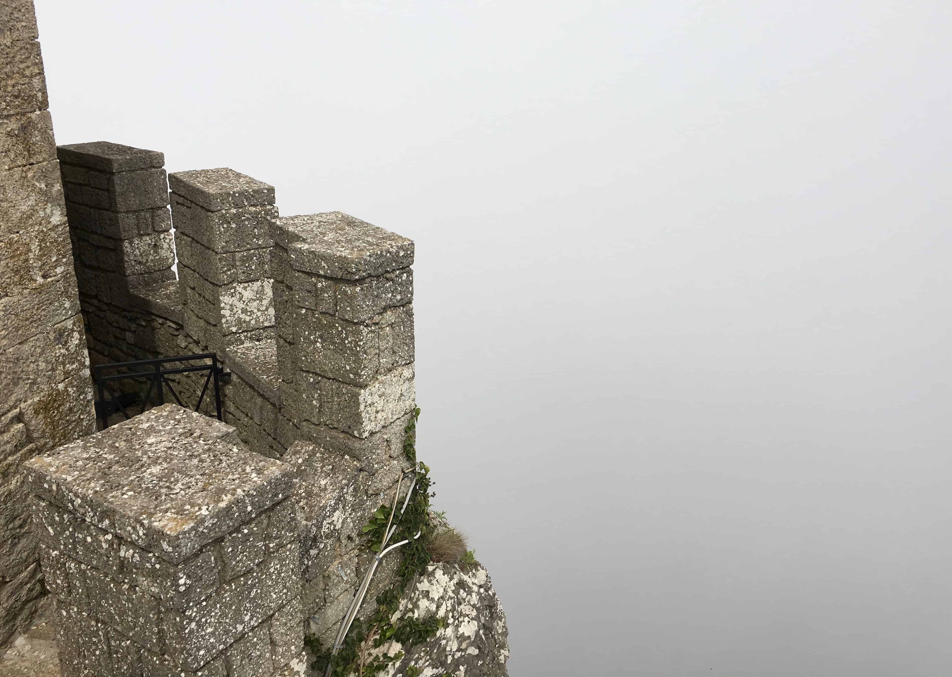 Mist shrouds the sheer drop from the walls of the Guaita fortress, San Marino