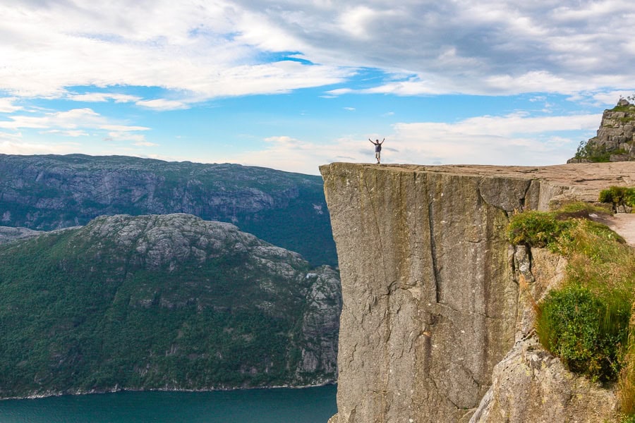 View of a lone person atop Preikestolen with Lysefjord in the background from the Pulpit Rock hiking trail.