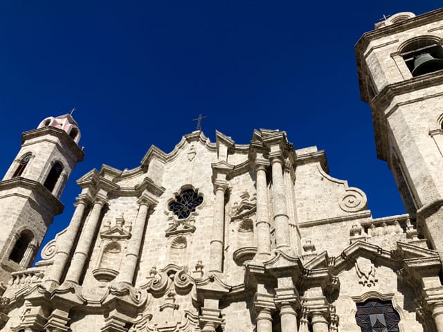 Blue sky forms a backdrop to the white stone facade of the Cathedral of Habana in Plaza de la Catedral.