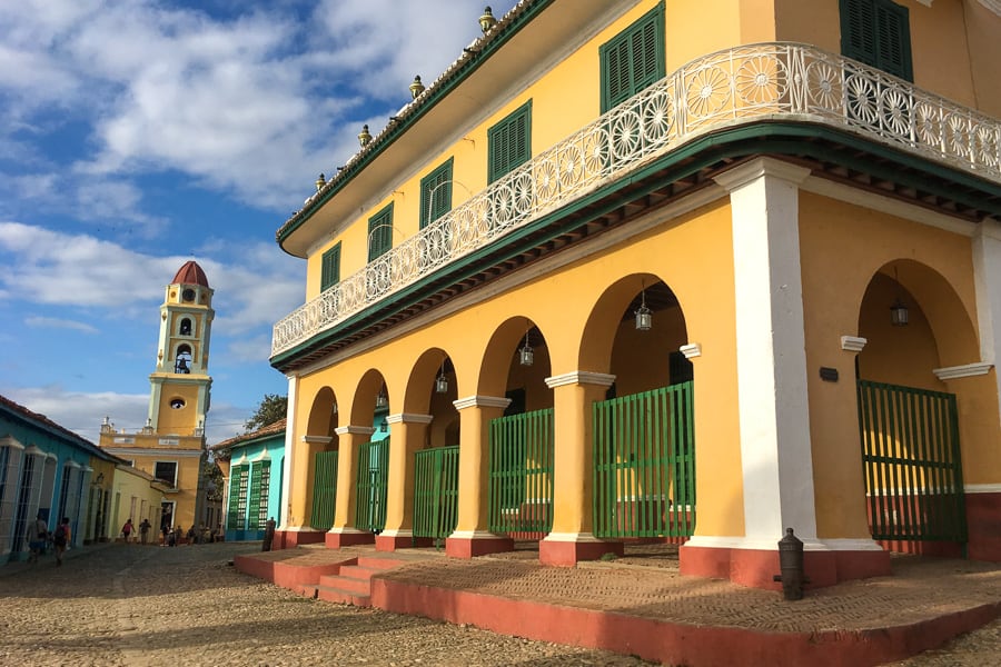 Cuba Trip Planner: A yellow colonial building and tower on a street in Trinidad.