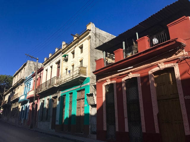 A row of blue, pink, green and red colonial houses on a walk through the streets of Havana, Cuba.