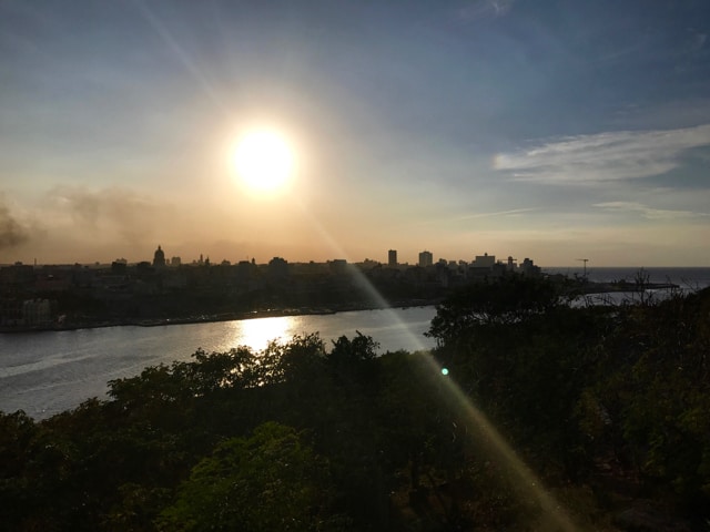 The sun begins to set over the silhouetted city of Havana, as seem from the Cristo de La Habana statue.