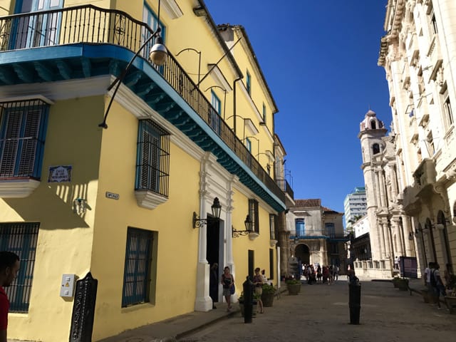 A yellow building with blue trim on a street in Havana.