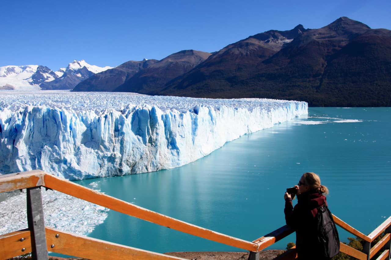 A girl waits for ice to fall from the north face of Perito Moreno Glacier.