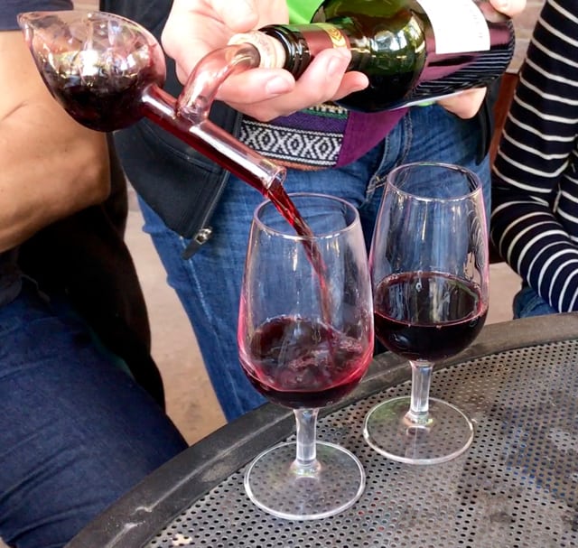 Red wine is poured into a tasting glass through a bottle-attached decanter on a wine tasting tour in Santiago.