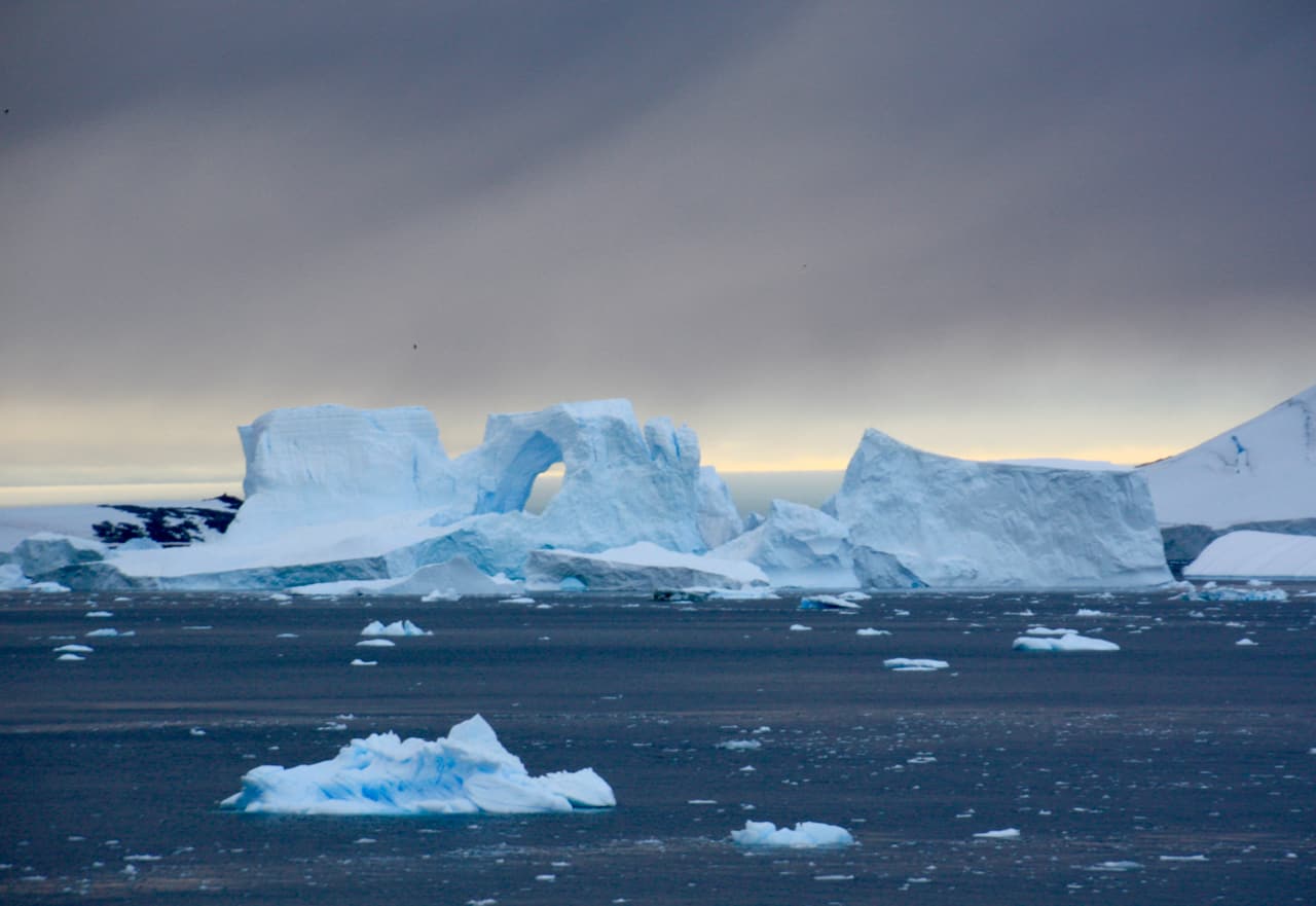 A huge iceberg with a massive natural archway is just one of the icy wonders that make for amazing photos of Antarctica. 