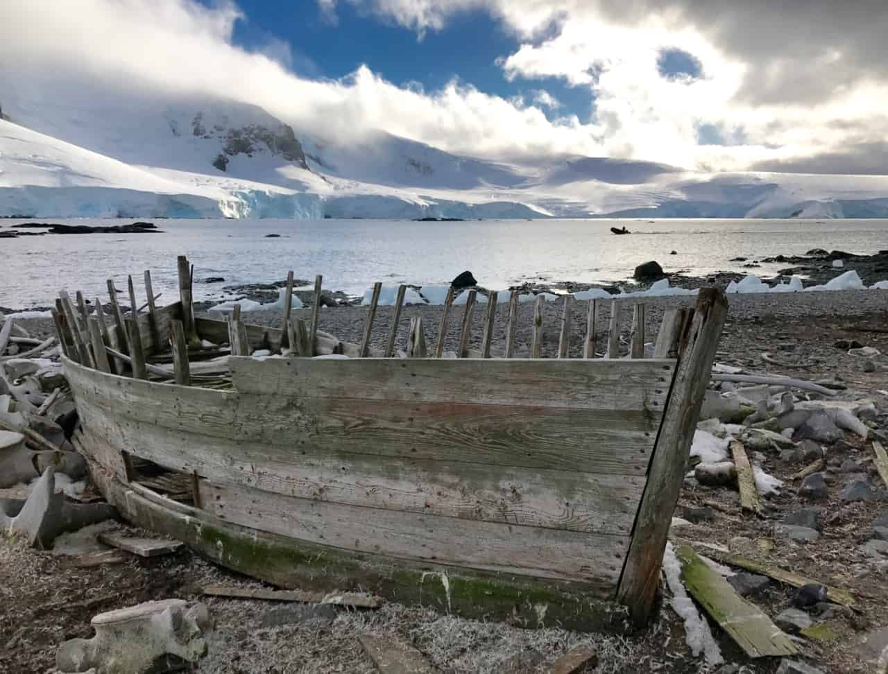 An old whaling boat sits abandoned on the shore at Mikkelson Harbour, surrounded by whale bones.
