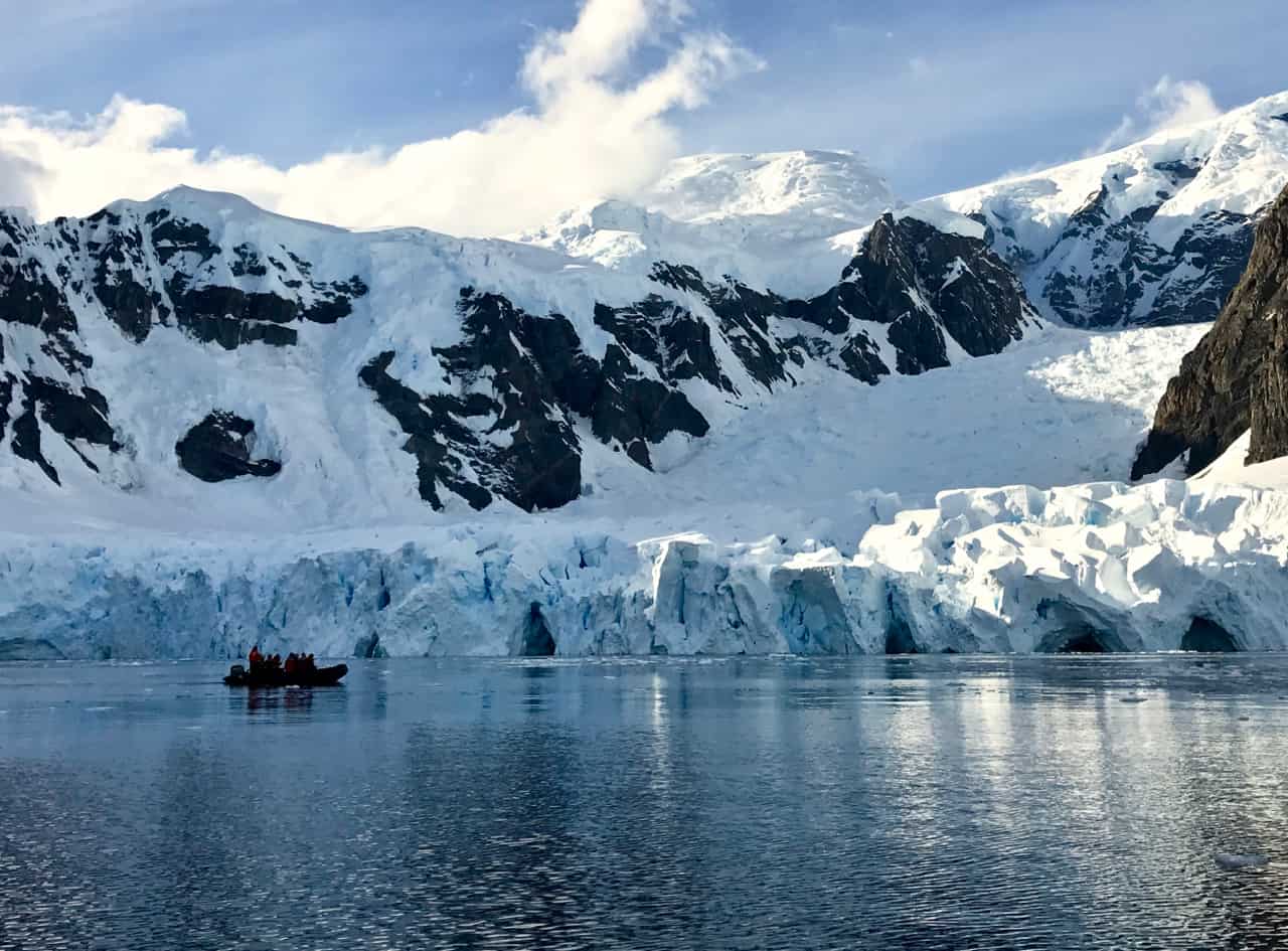 A zodiac boat cruises in front of the glacier at Paradise Bay in Antartica.
