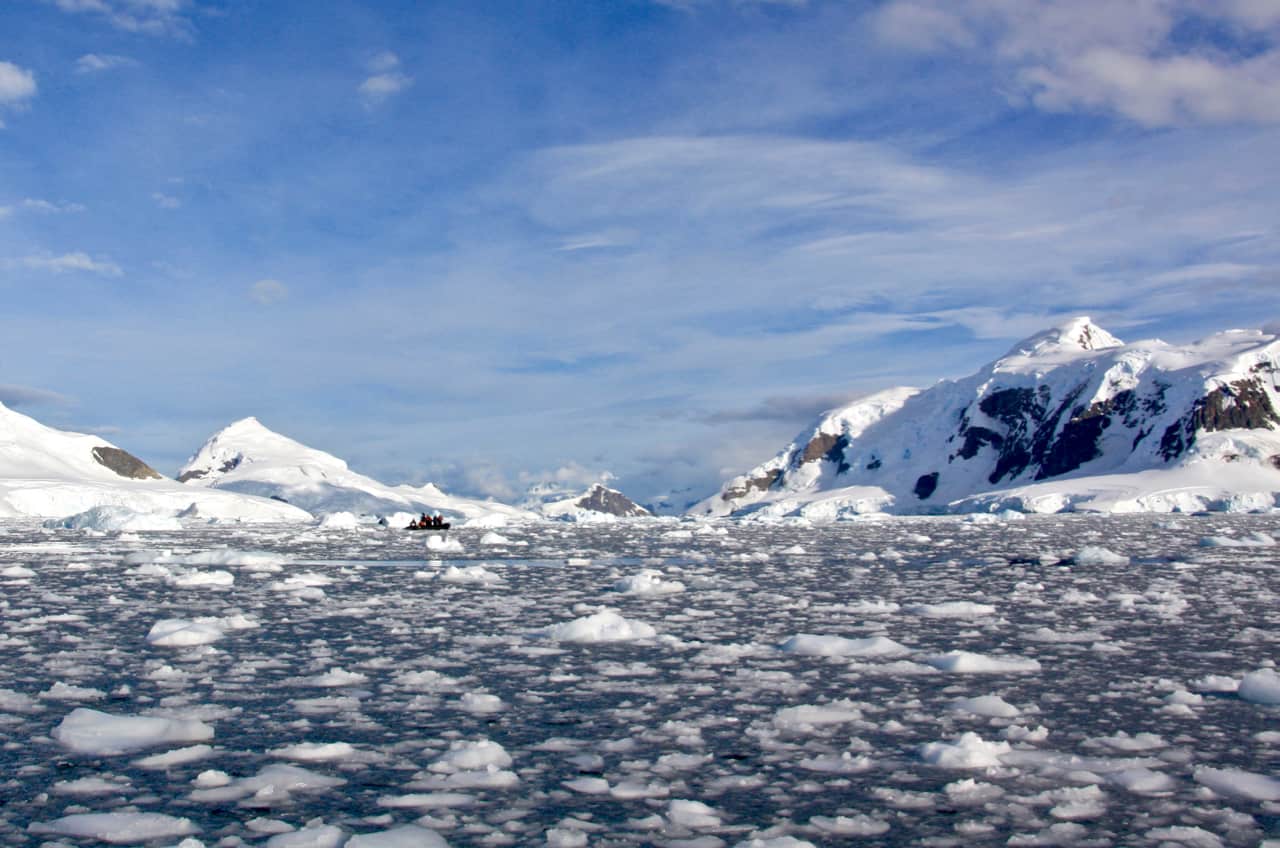 A zodiac cruises on a bay beginning to thicken with ice as winter approaches in this image of Antarctica. 