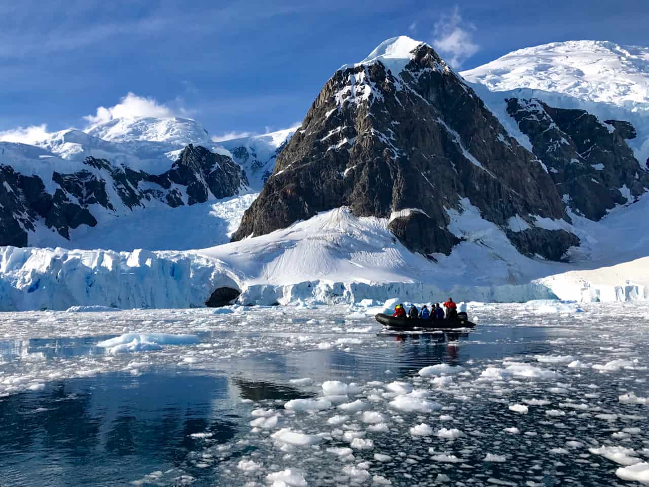 A zodiac cruises through slushy Paradise Bay towards an epic glacier in one of our favourite photos of Antarctica.