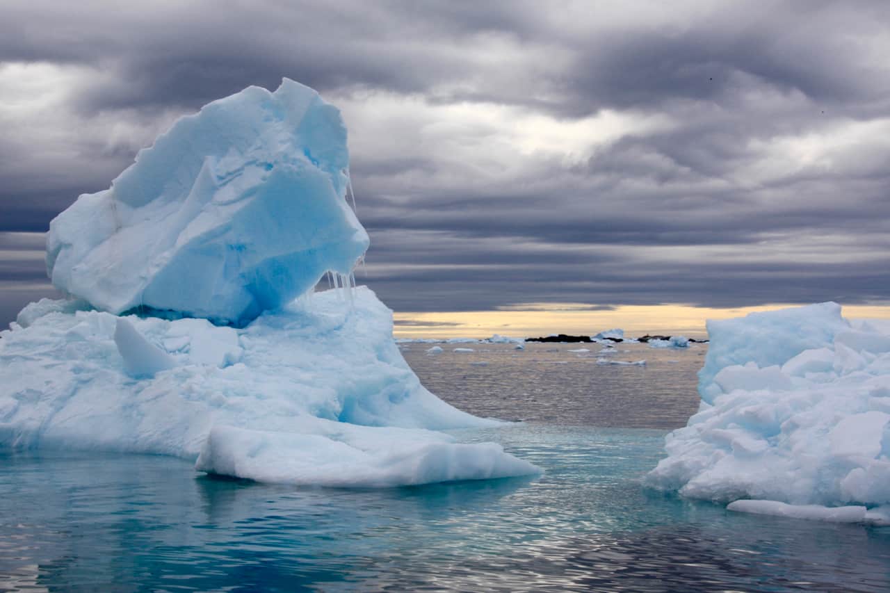 A bright blue iceberg is backed by a dark and foreboding sky in one of our favourite berg photos of Antarctica.