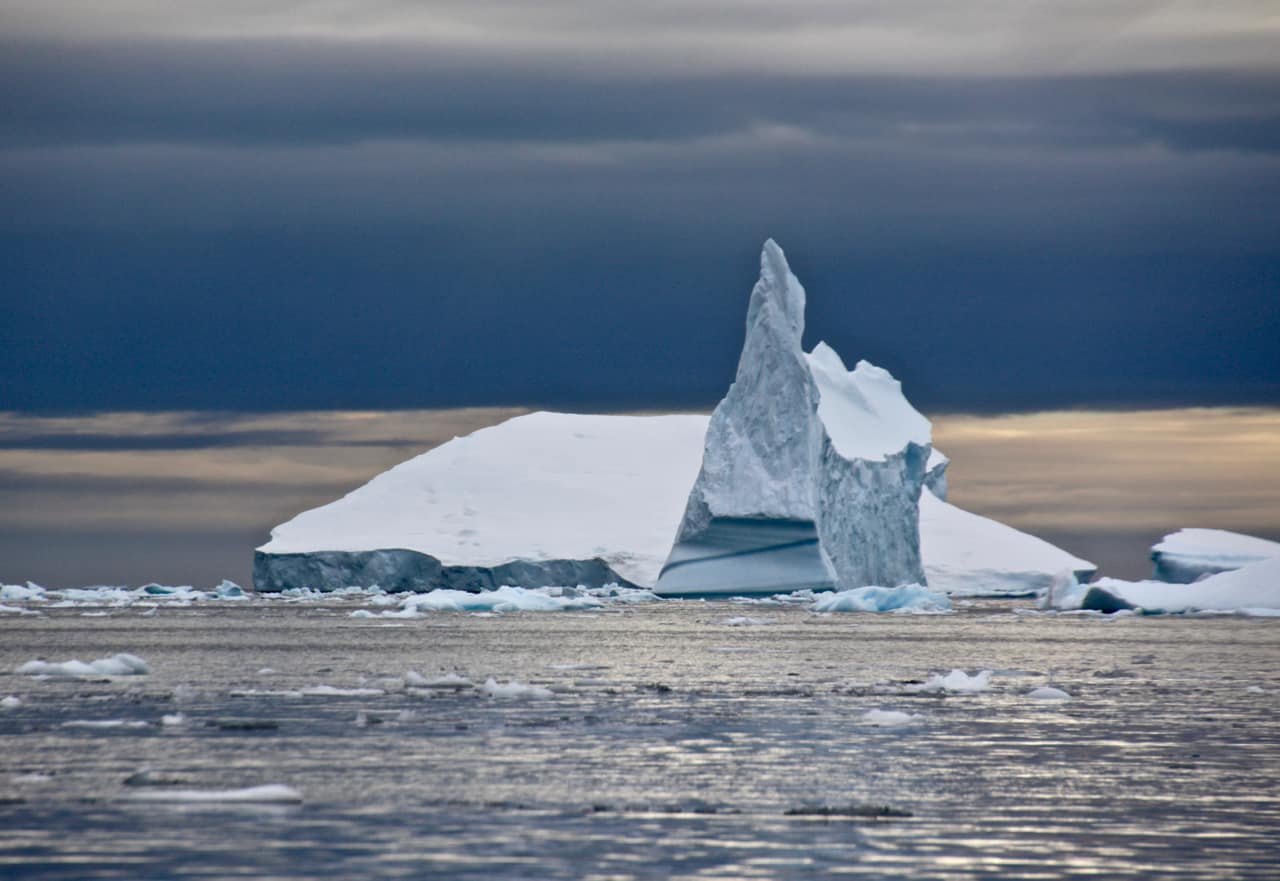 A huge iceberg shard rises into a dark sky in Antarctica.