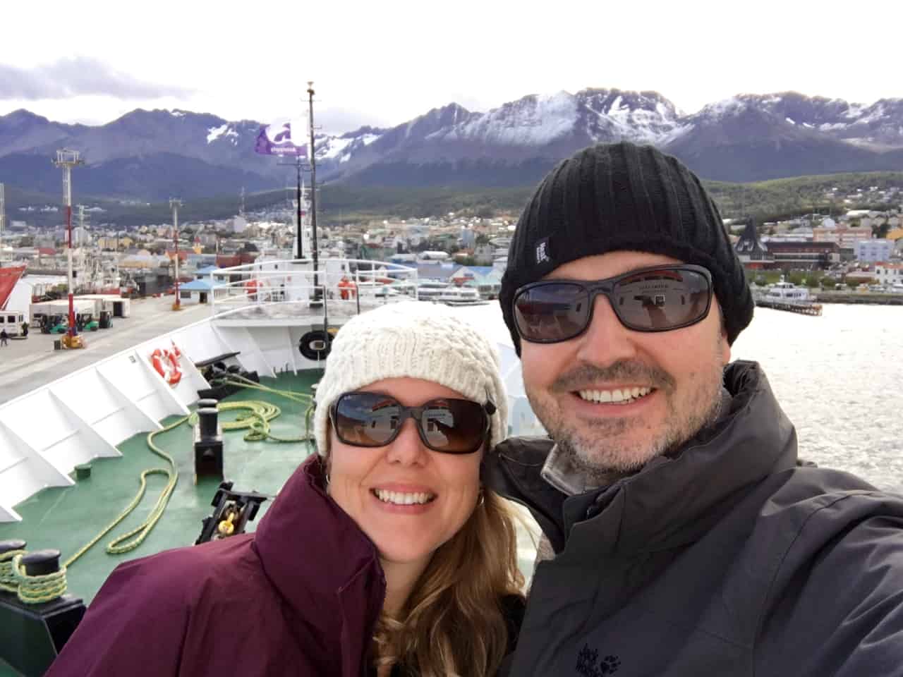 Happy couple aboard the expedition ship, MV Ushuaia, with the town of Ushuaia in the background. 