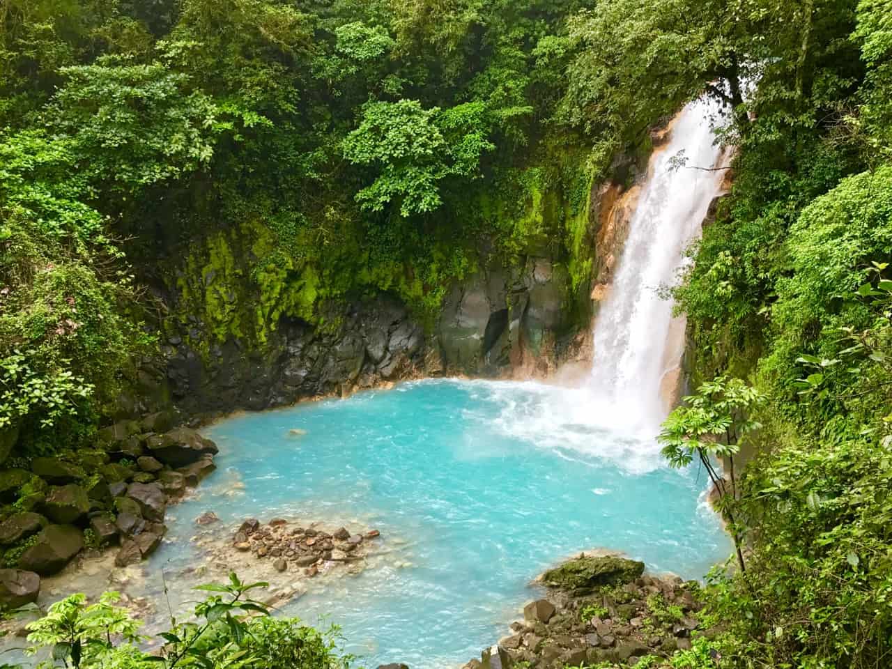 Rio Celeste-fossen stuper inn i et melkeblått basseng Ved Tenorio Volcano National Park, en av De mindre besøkte parkene I Costa Rica.