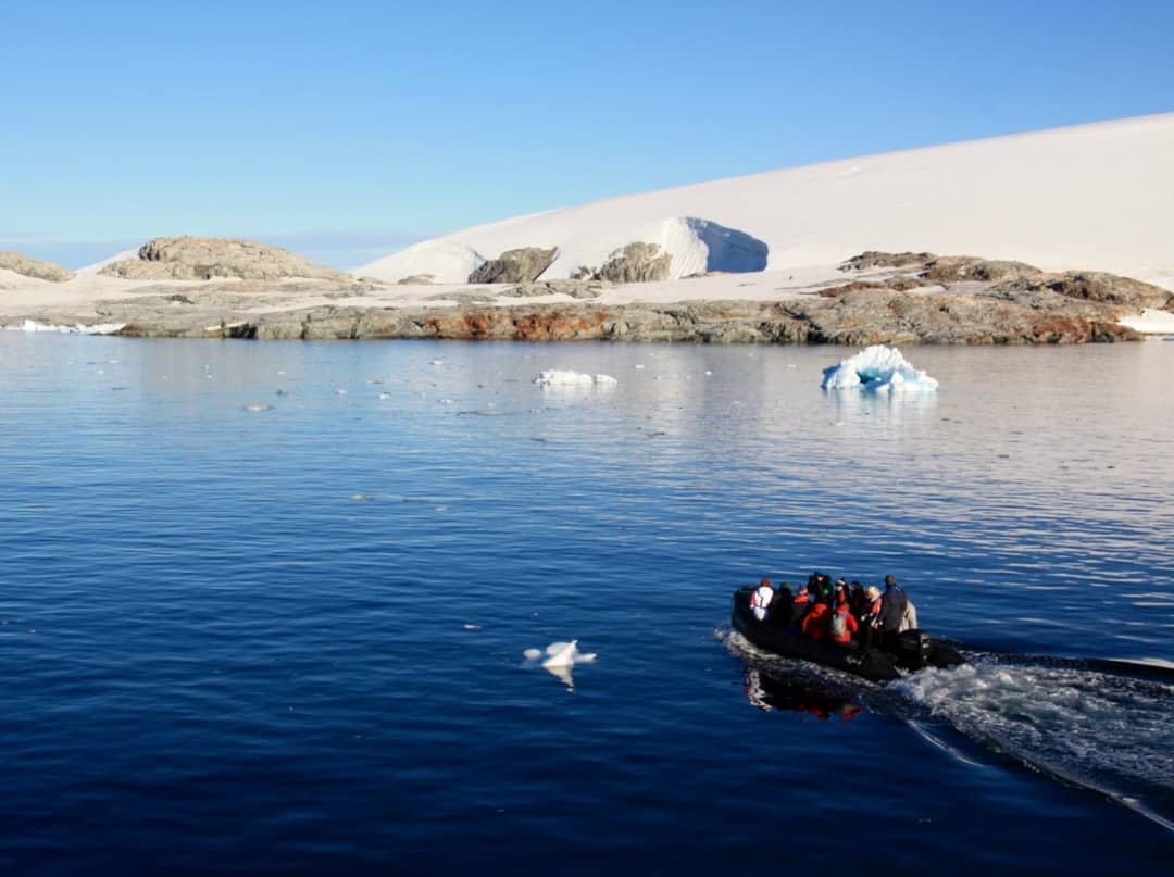 A zodiac boat takes passengers from an Antarctica cruise to visit a research station.