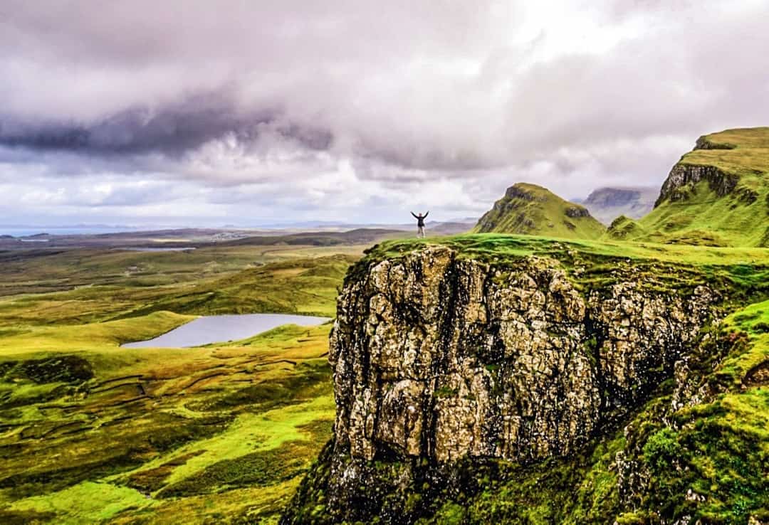 Dan stands atop a cliff on the Quiraing, a highlight of any Isle of Skye road trip.