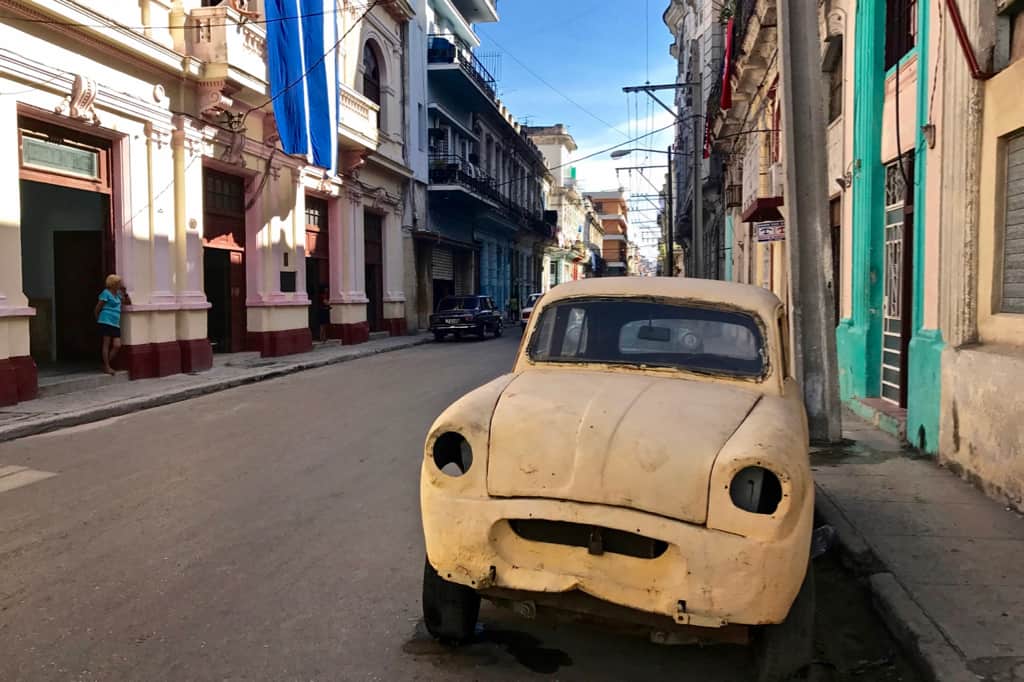 An old yellow car on a street scene in Havana, Cuba.