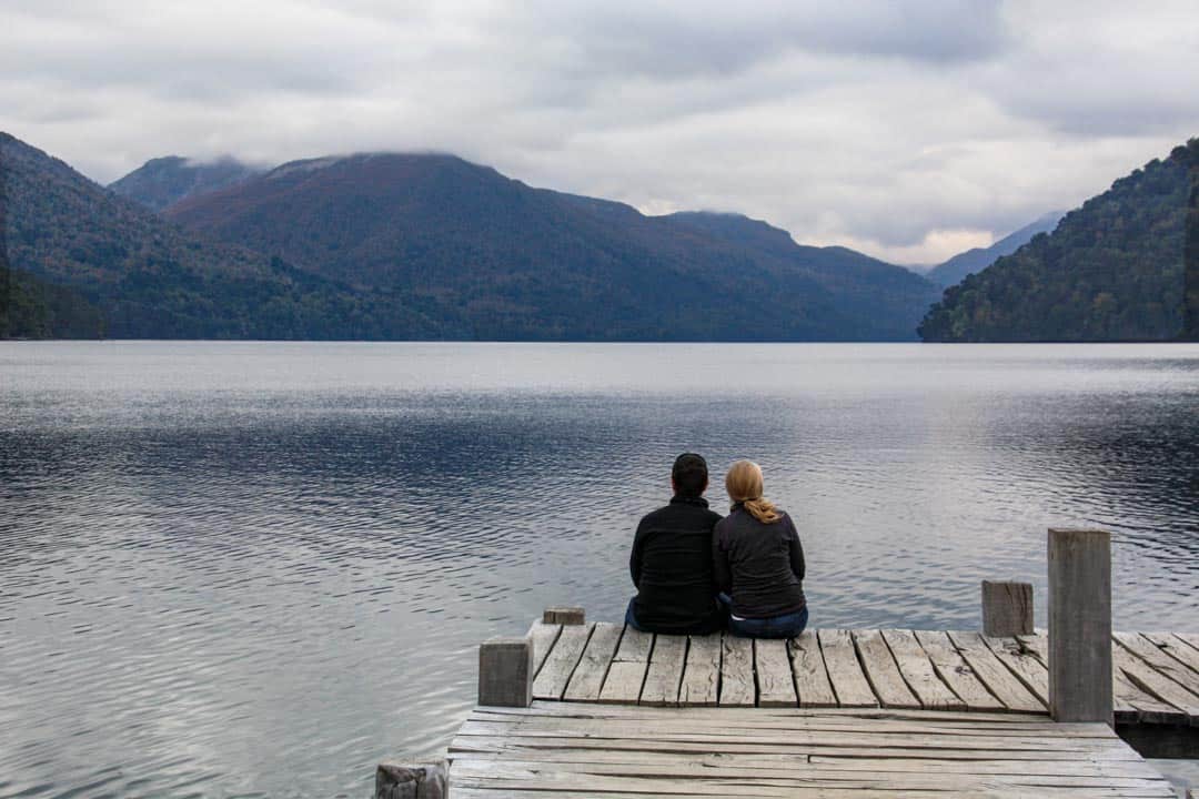 Two sit on a pier jutting out into Lake Hermoso on the Ruta de los 7 Lagos.