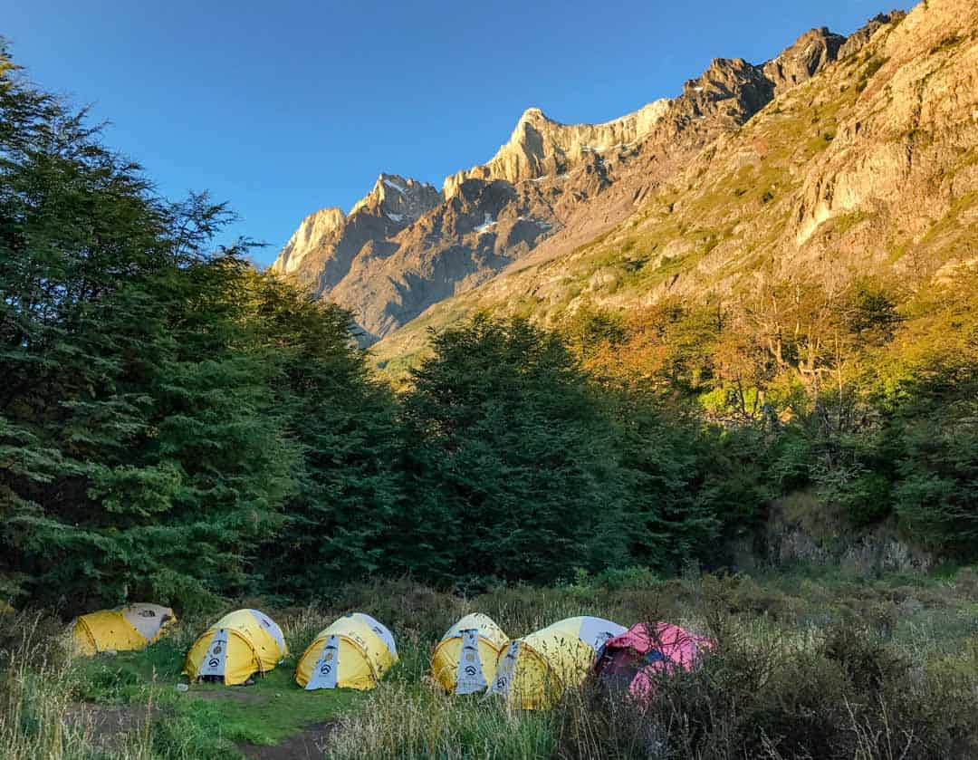 Tents cluster under the golden glow of the Olguin mountains in Torres del Paine.