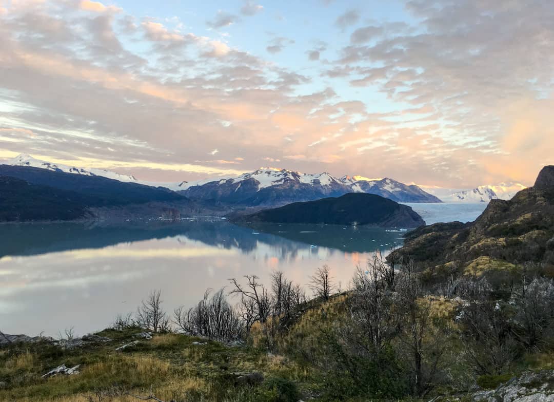 Dawn turns the clouds orange over Grey Lake on the W trail Patagonia.