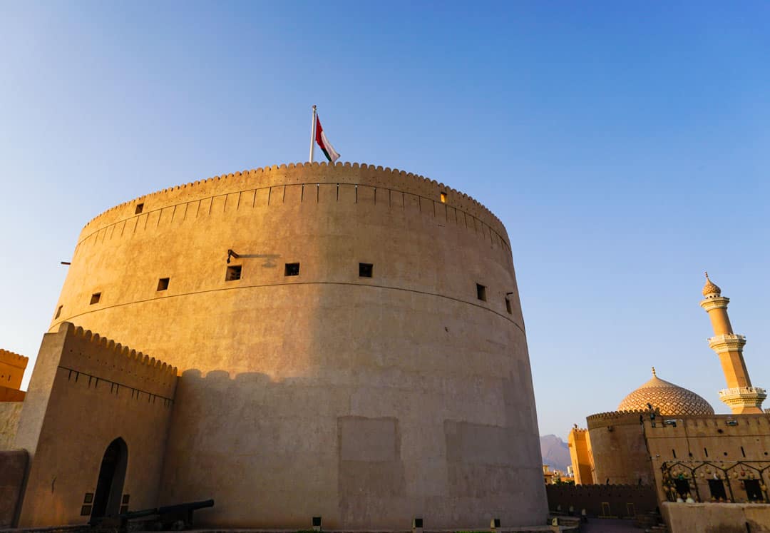 Time your Oman Itinerary to see the vast tower of Nizwa Fort and the nearby mosque turn burnt orange at sunset.