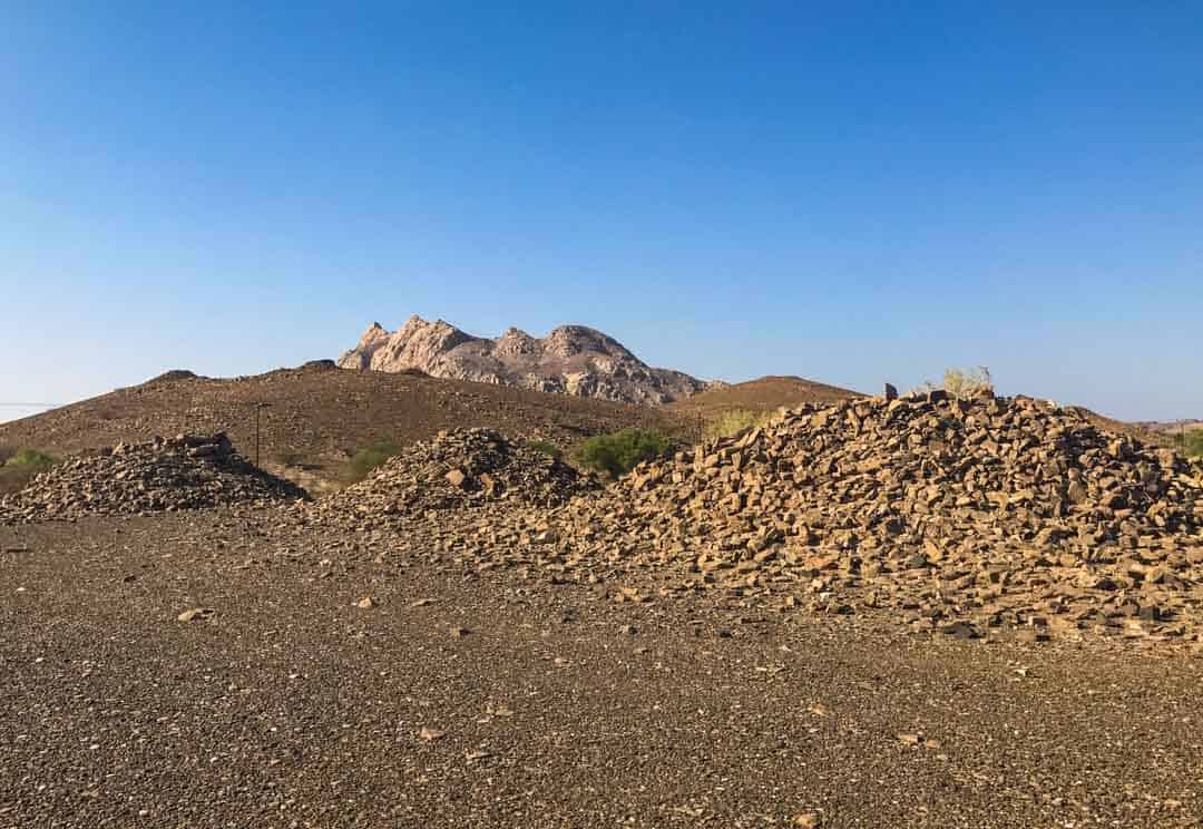 Piles of stone dot the landscape at the off-the-beaten track ancient site of Bat – a must visit site as you road trip Oman.