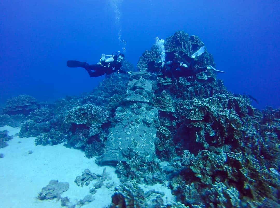Divers at the fake sunken moai in Hanga Roa harbour on an Easter Island diving trip.
