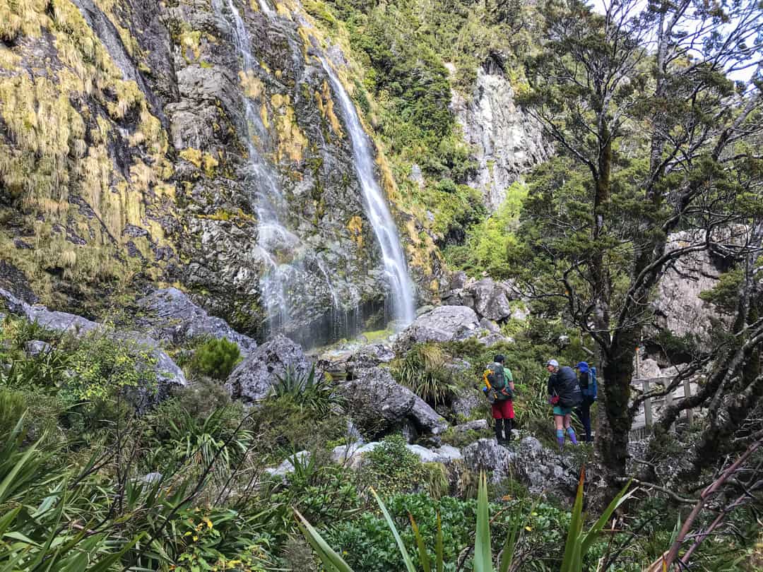 Hikers At The Foot Of Earland Falls On The Routeburn.