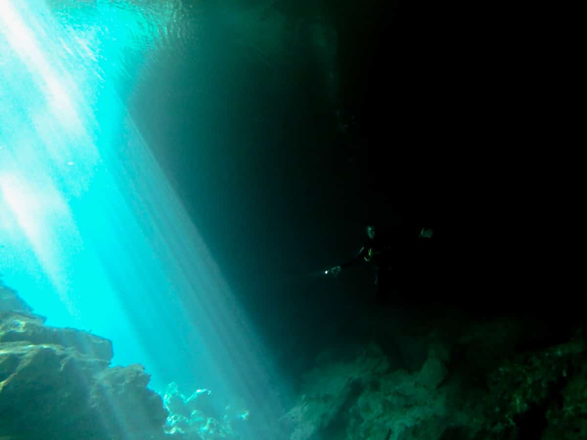 A diver next to the refracting light of Jardin del Eden cenote Mexico.