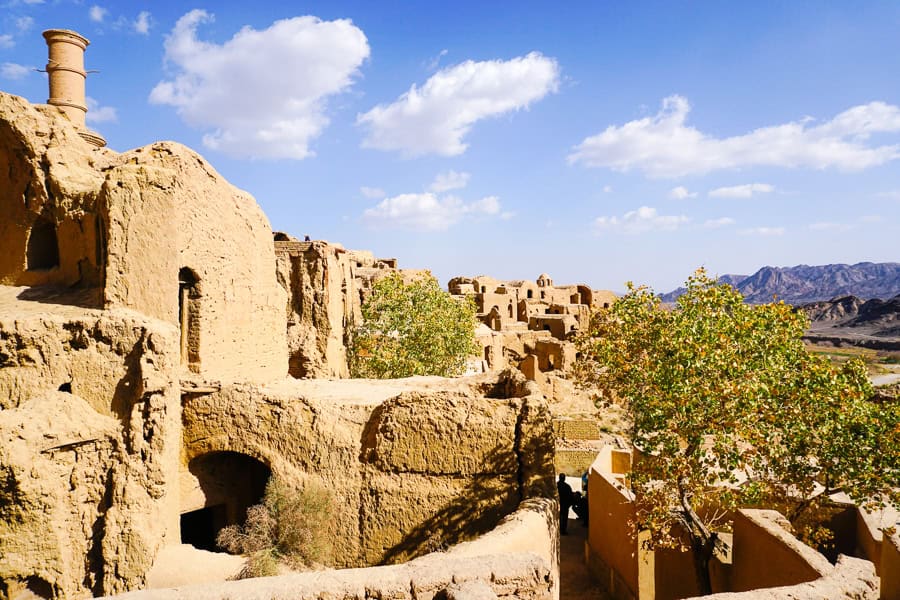 The mud brick houses of Kharanagh bake in the sun with mountains in the distance – one of our unexpected Iran highlights.