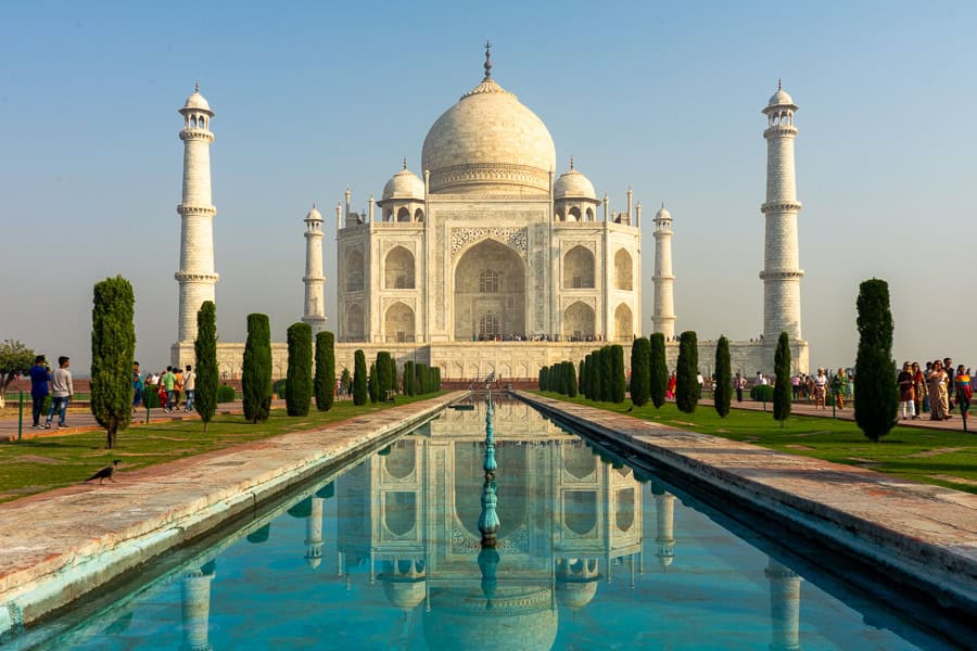 The Taj Mahal reflected in a blue pool on a clear, sunny day, a visit here is the highlight of an India road trip.