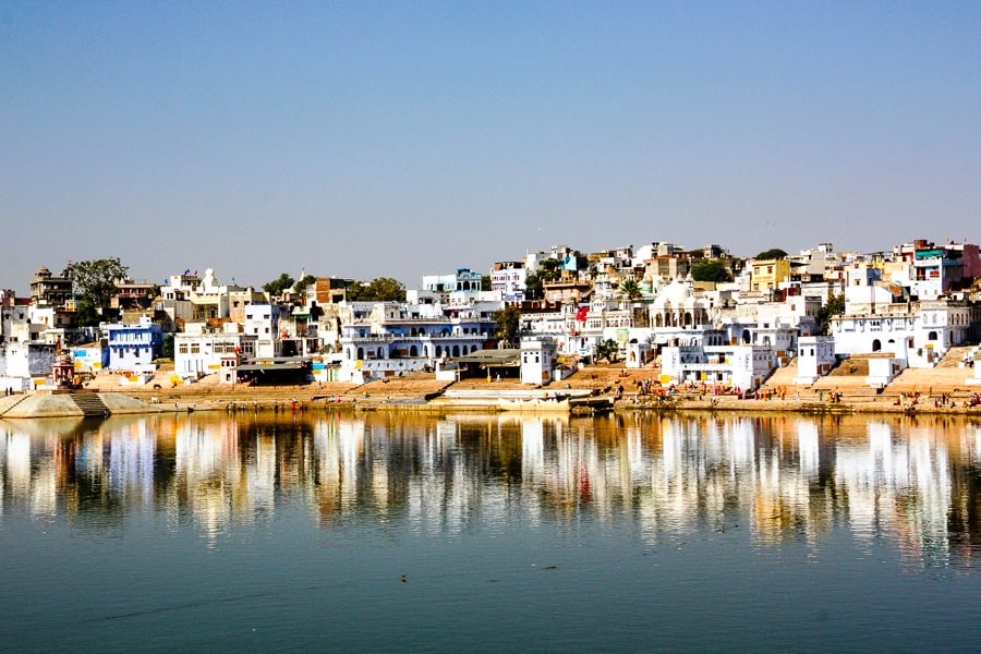 Houses and temples are reflected on tranquil Pushkar Lake – a visit that should be included on your Rajasthan itinerary.