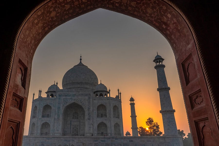 The Taj Mahal seen through an archway at sunrise, the ultimate highlight of Rajasthan road trip itinerary for India.
