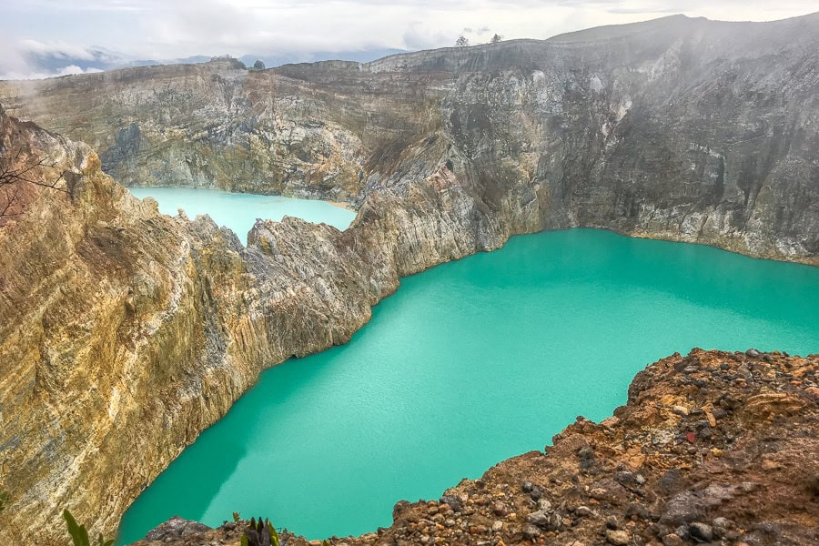 View of the iridescent crater lakes of Kelimutu from above the rim of the crater – the highlight of out Flores itinerary.