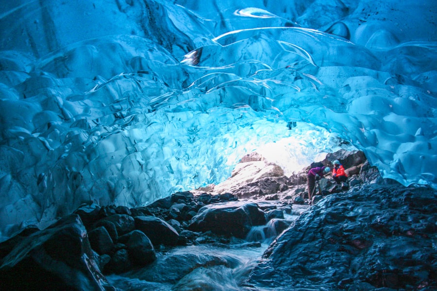 Smooth blue ice glistens across the curving ceiling of an Icelandic ice cave.