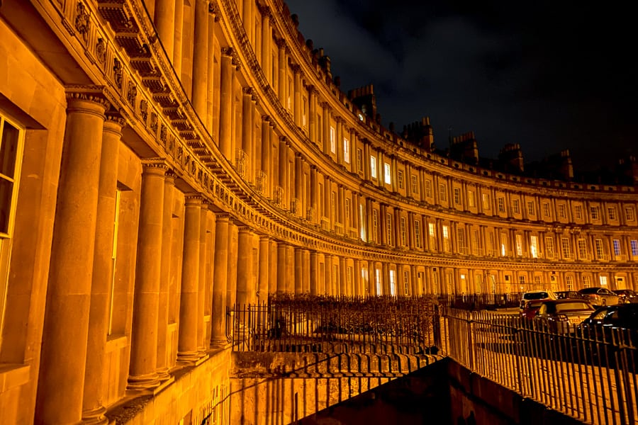 A curve of columned building on the Circus in Bath, lit up at night.