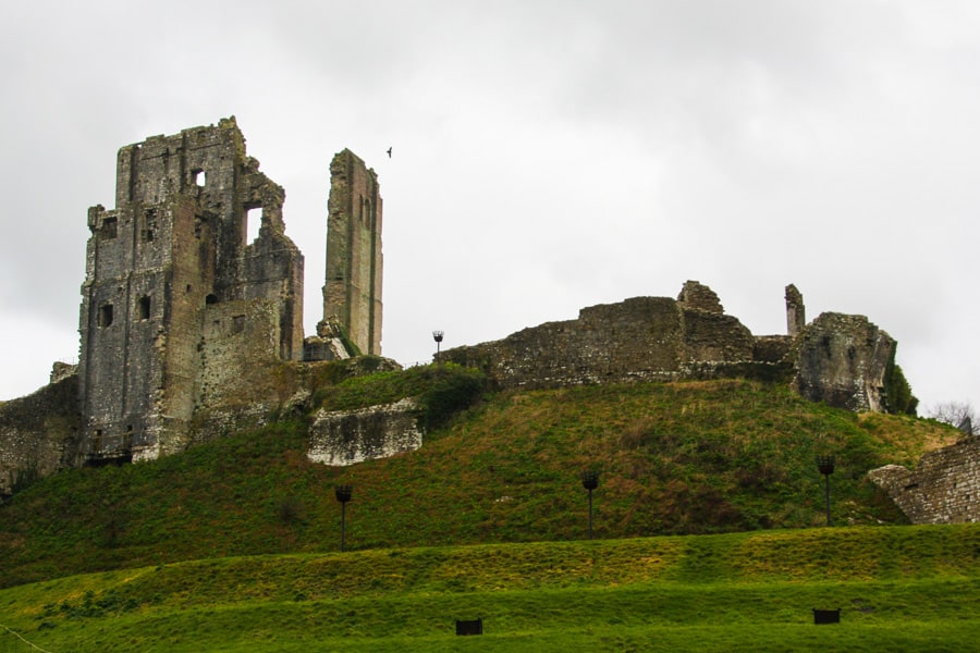 The stone ruins of Corfe Castle sit high atop a green hill.