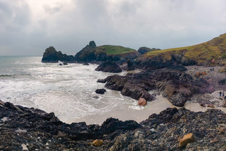 Waves crash on the rocky shore of Kynance Cove, highlight of a road trip to Cornwall.