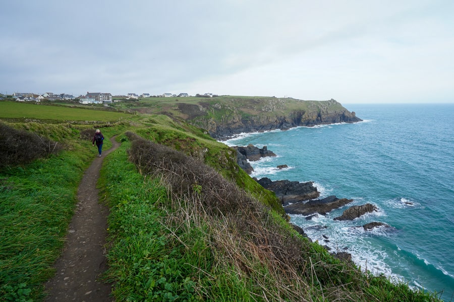 A person walking on a path by the ocean at Lizard Point, Cornwall. 