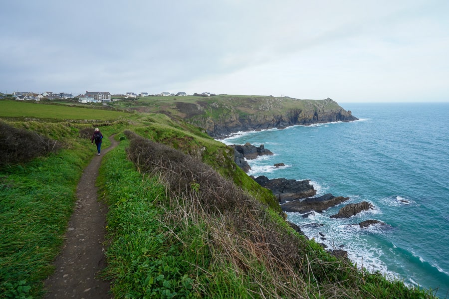 A person walking on a path by the ocean at Lizard Point, Cornwall. 