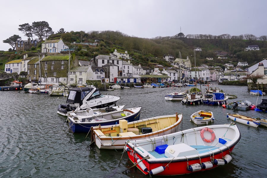 Boats in a harbour backed by white buildings in Polperro, a fishing village in south west England.