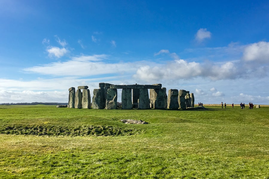 Looking across a green field towards Stonehenge, highlight of a south west England road trip.