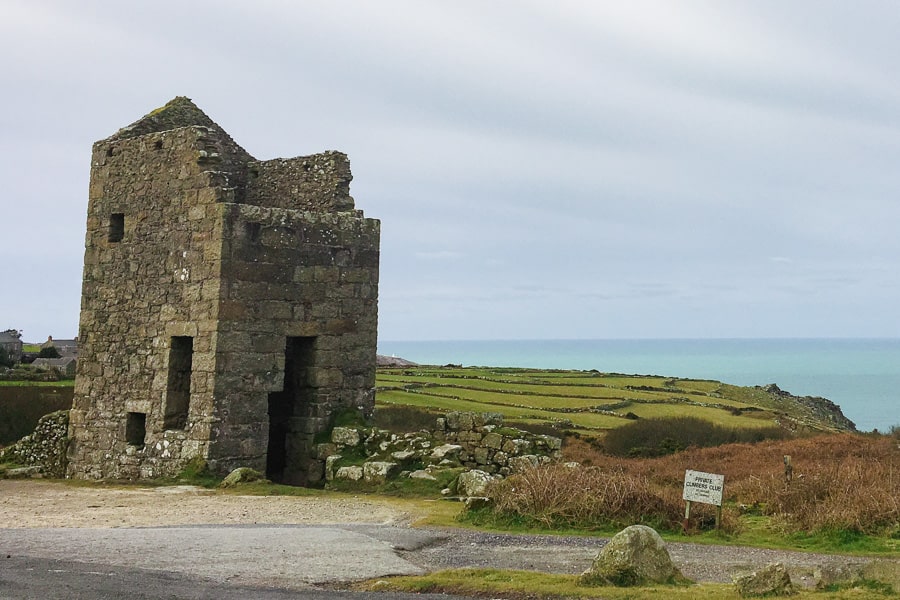 A ruined tin mine building with fields and ocean in background on a south west England road trip.
