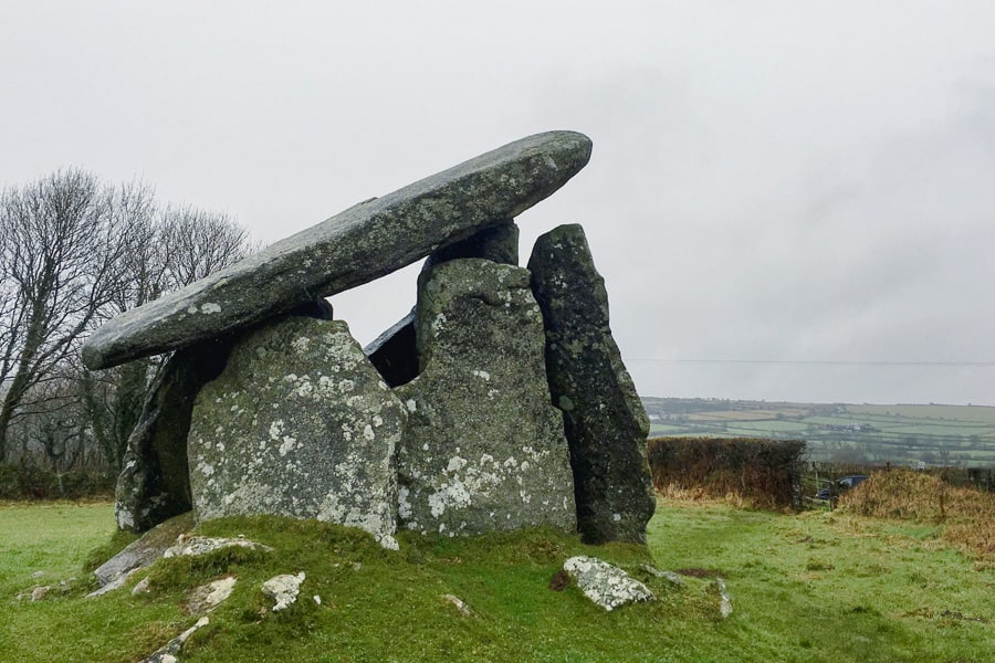 An ancient stone structure stands in a green field.