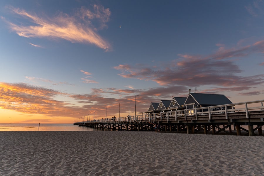 Clouds glow golden and pink above Busselton Jetty at sunset, highlight of a Western Australia road trip.