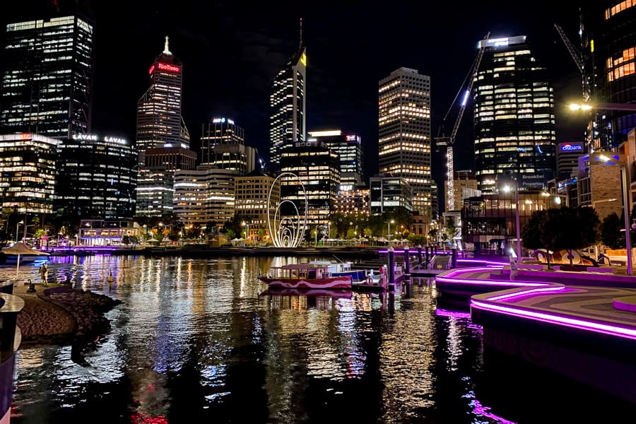 Buildings lit up at night above the water of Elizabeth Quay, city highlight of a Perth road trip.