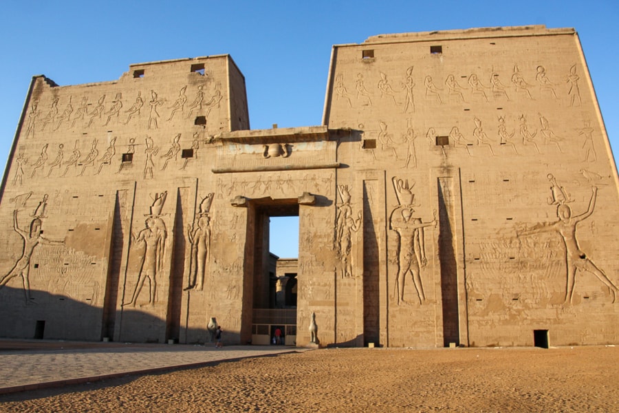 The high entrance pylon of Edfu Temple decorated with giant reliefs of the pharoah smiting his enemies before the god Horus. 