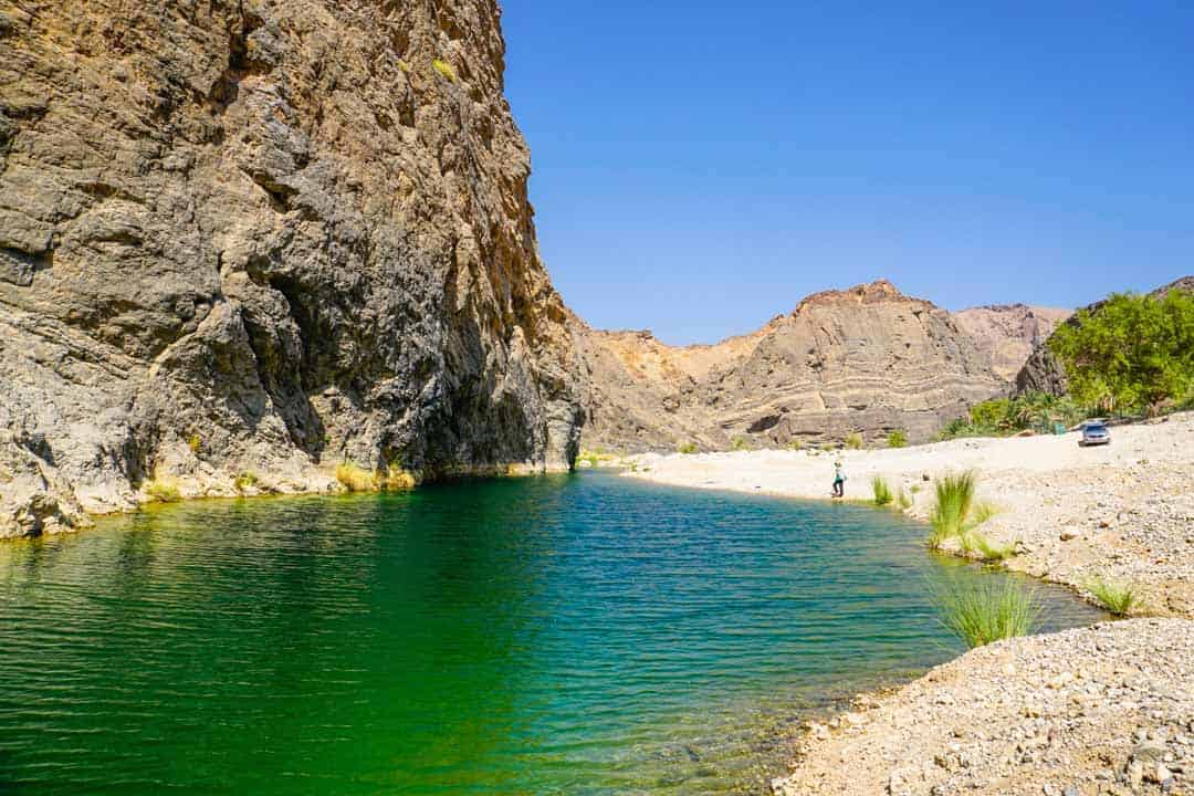 The emerald water of Wadi Al Arbeieen starkly contrast the parched surroundings on this leg of our Oman road trip itinerary. 